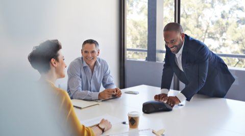 People sitting at a conference table, one man is leading the call.